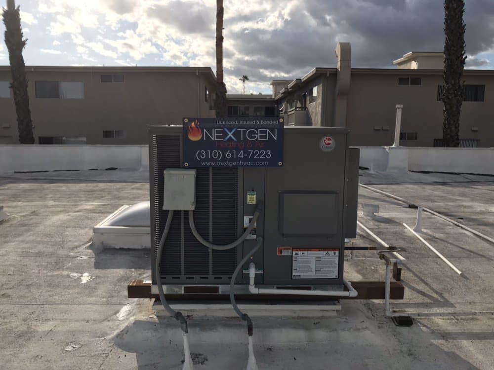 New Rheem rooftop package unit installed by NextGen Heating and Air, their banner zip-tied to the coil guard, Van Nuys apartment building